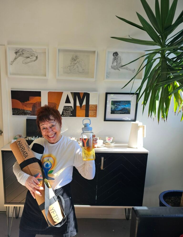 Hariata holding a drink bottle and yoga mat in the yoga studio