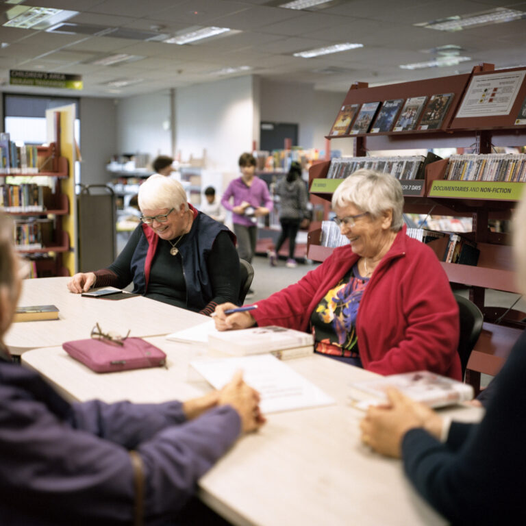 Two older adults in a library talking