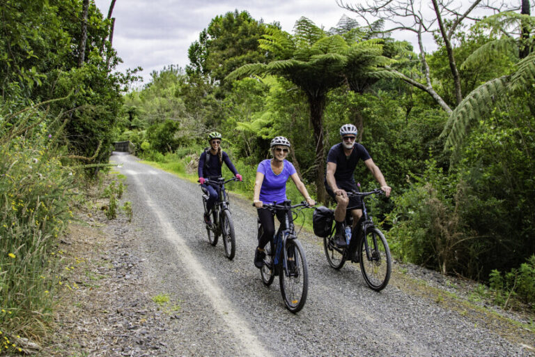 Three older adults on bikes along a paved road