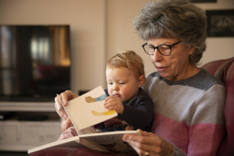 Older adult reading a book to a baby
