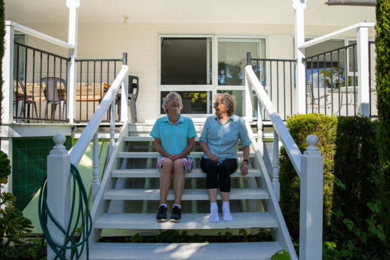 Two older persons sitting on the front porch steps