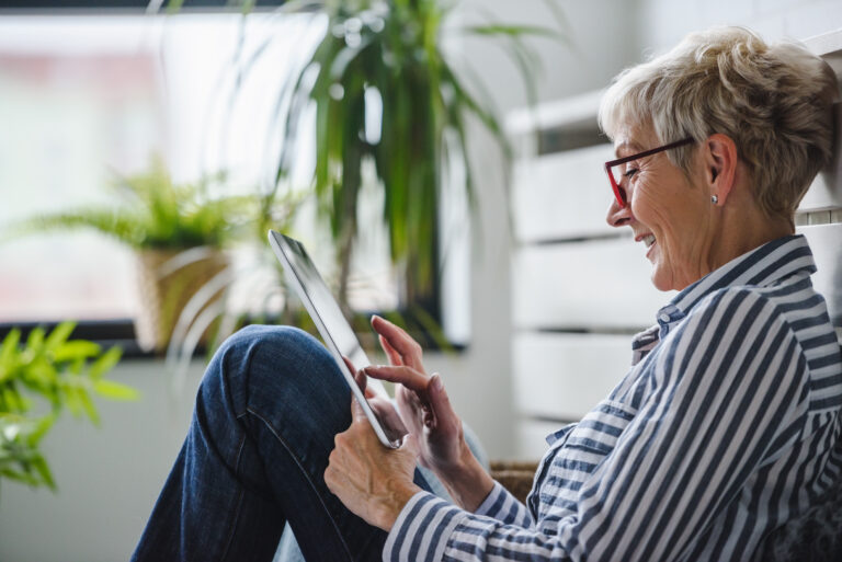 Older adult sitting white looking at a tablet