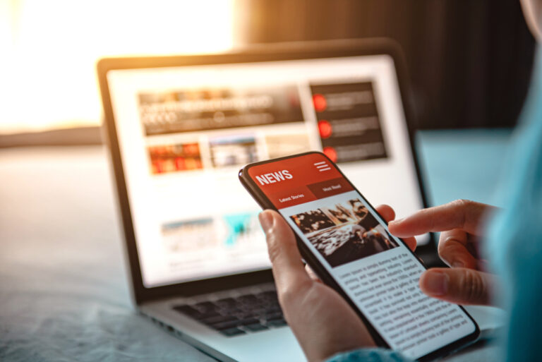 Phone and laptop showing the news