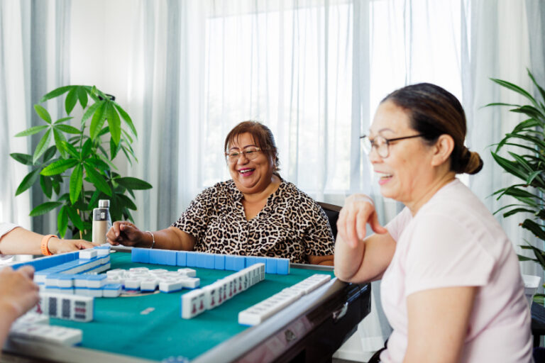 Two older adults playing mahjong