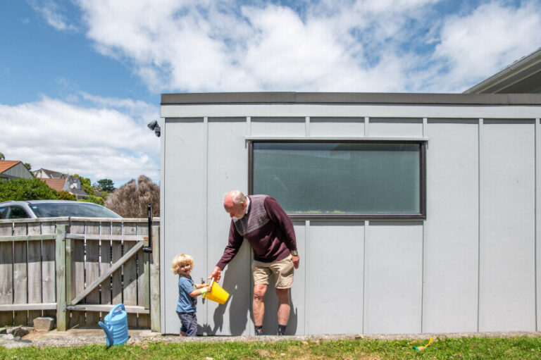 Older adult with young child standing in front of a garage