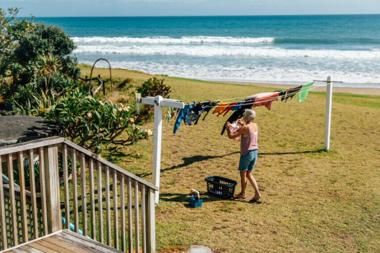 Older adult hanging washing with a beach in the background