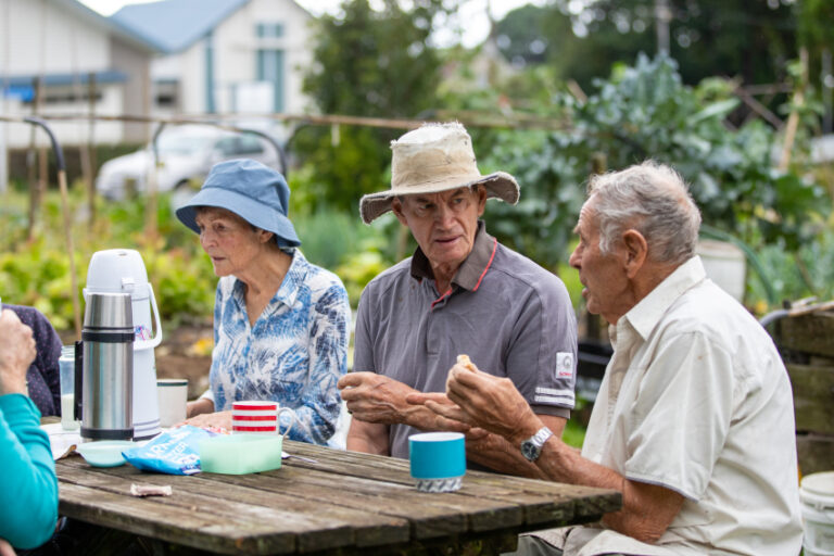 Older adults eating food in a picnic table outdoors