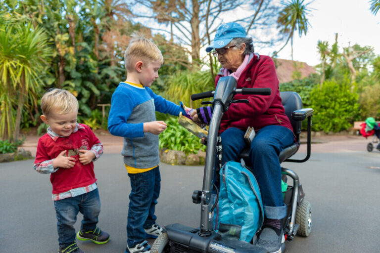 Older adult in a mobility scooter talking to two young children