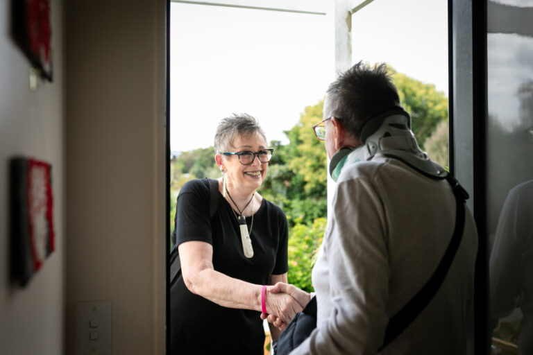 Two older adults shaking hands by the doorway